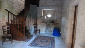 A rustic interior with a stone wall, wooden staircase, and a blue tablecloth-covered table.