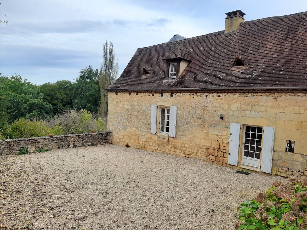 Ein Steinhaus mit Kieshof, zwei Fenster mit Rollläden und einem geneigten Dach.