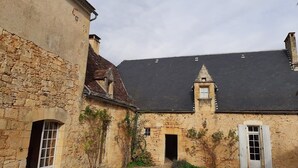 A courtyard with stone buildings, a small tower, and a gravel path.