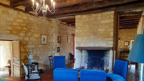 A rustic room with stone walls, a fireplace, and blue upholstered chairs.