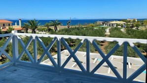 A balcony with a white railing overlooking a coastal area with houses, a clear blue sky, and a view of the sea. - Romantic Villa with Private Pool & Whirlpool (Πύργος)