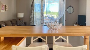 A modern living room with a wooden dining table, white chairs, a patterned curtain, and a view of the outdoors. - Romantic Villa with Private Pool & Whirlpool (Πύργος)