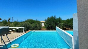 A swimming pool with clear blue water, surrounded by greenery and a view of the sea. - Romantic Villa with Private Pool & Whirlpool (Πύργος)