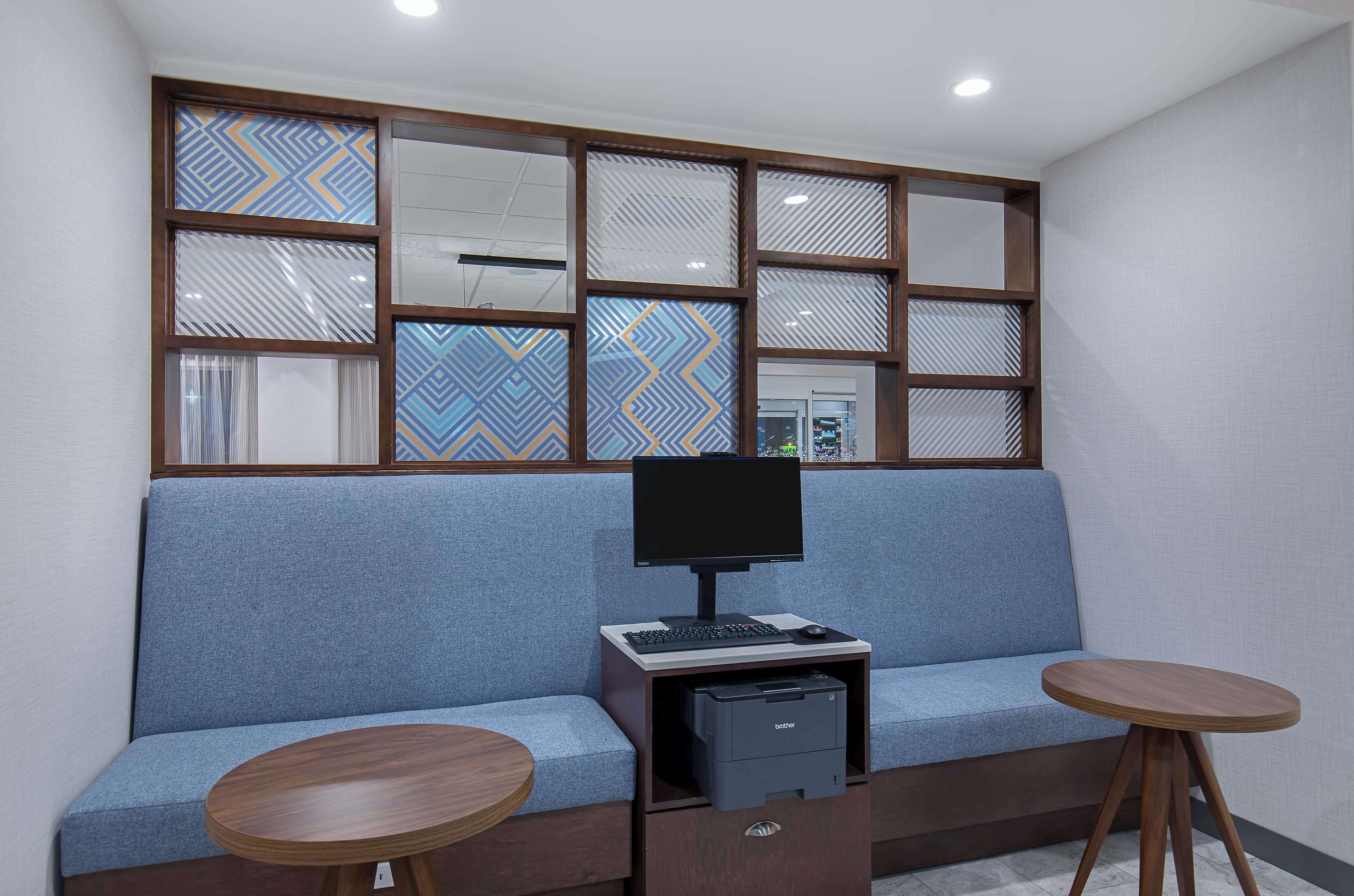 Una habitación moderna con un sofá azul, un escritorio con una computadora e impresora.