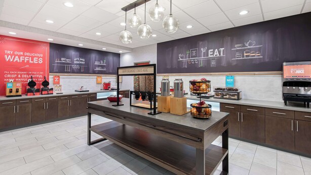 Een moderne keuken met een centraal aanrecht, een wafelstation en een koffieapparaat.