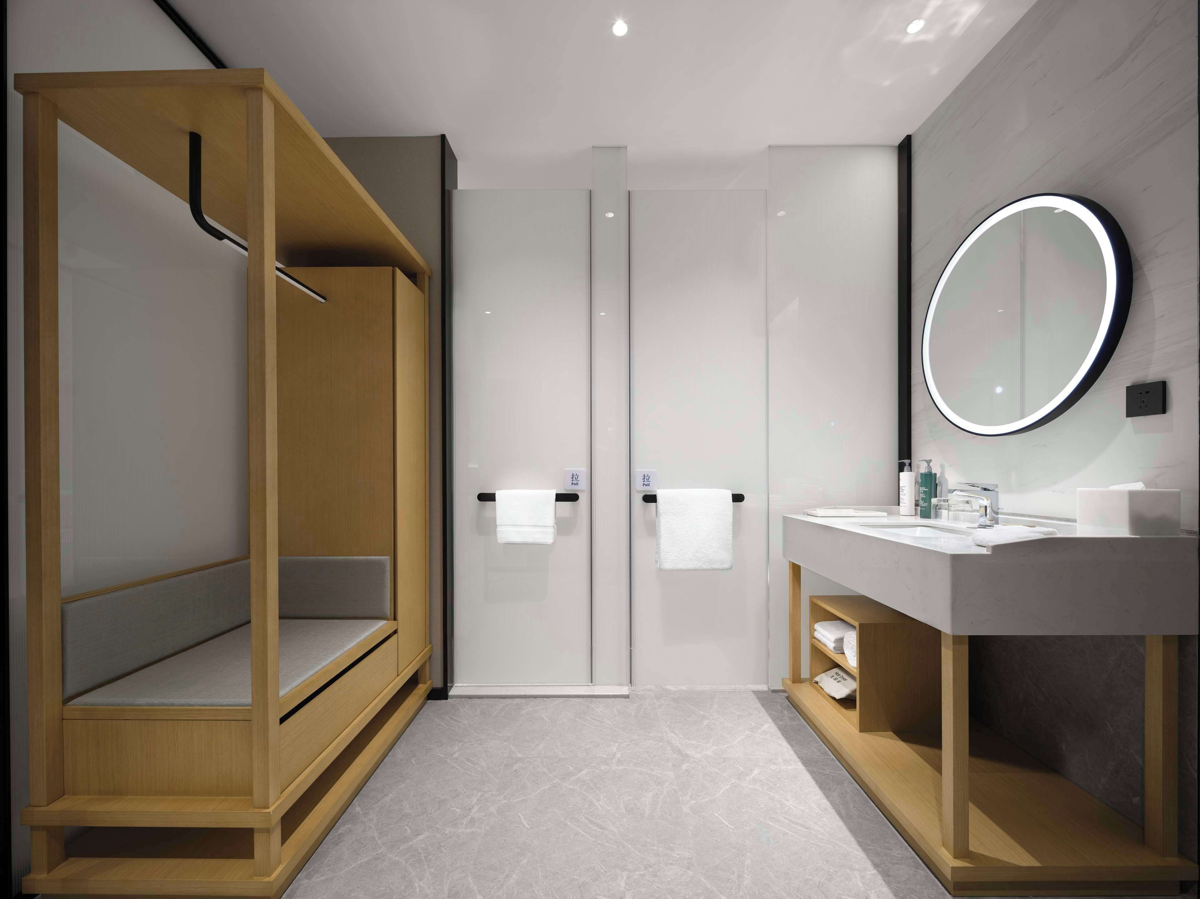 A modern bathroom with a wooden walk-in shower, a glass-enclosed toilet, and a vanity with a mirror.