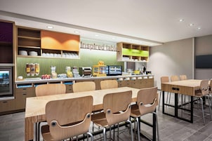 Un comedor moderno con mesas y sillas de madera, una barra con productos alimenticios y un letrero que dice "inspired table".