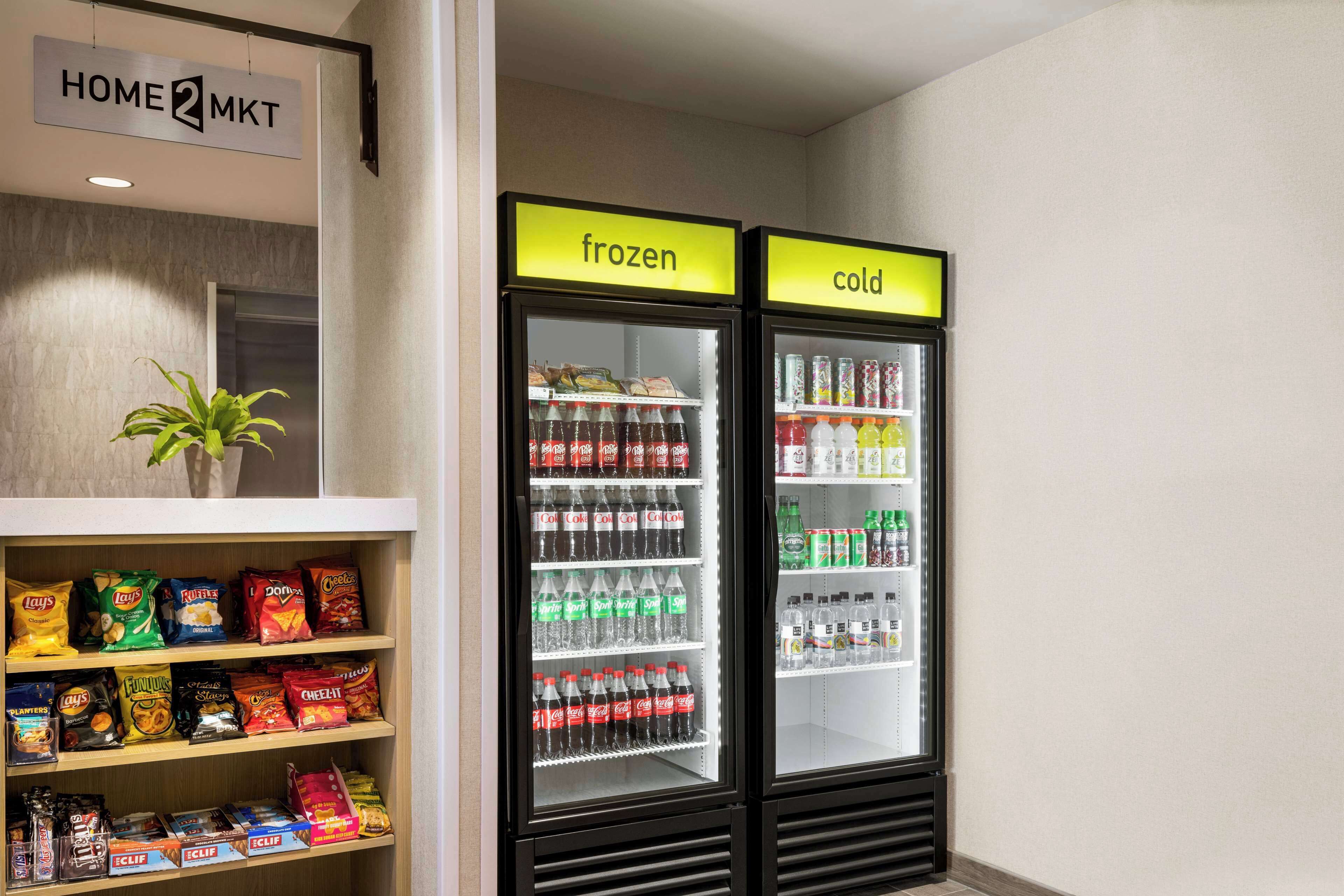 Une petite cuisine équipée d’une étagère remplie d’en-cas et d’un congélateur contenant des boissons.