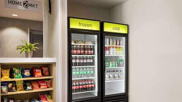 Une petite cuisine équipée d’une étagère remplie d’en-cas et d’un congélateur contenant des boissons.