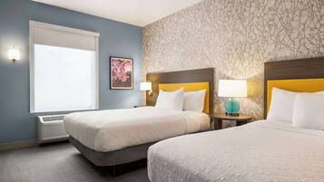 A hotel room with two beds, a window with blinds, a wall-mounted air conditioner, and a patterned wallpaper.