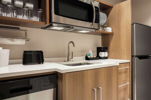 Una cocina moderna con electrodomésticos de acero inoxidable, lavavajillas y armarios de madera.