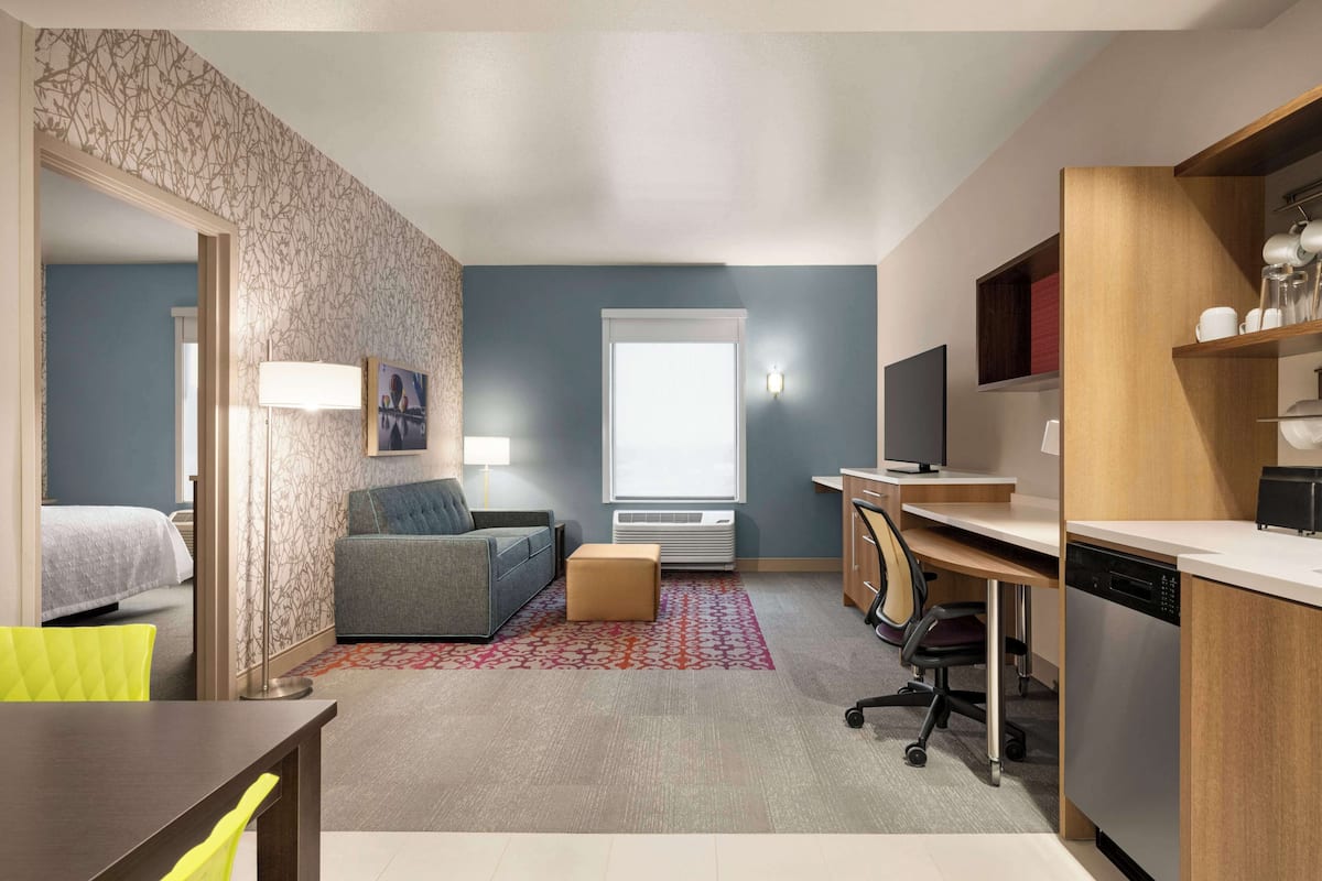 Een moderne hotelkamer met een bed, een slaapbank, een bureau en een kitchenette.