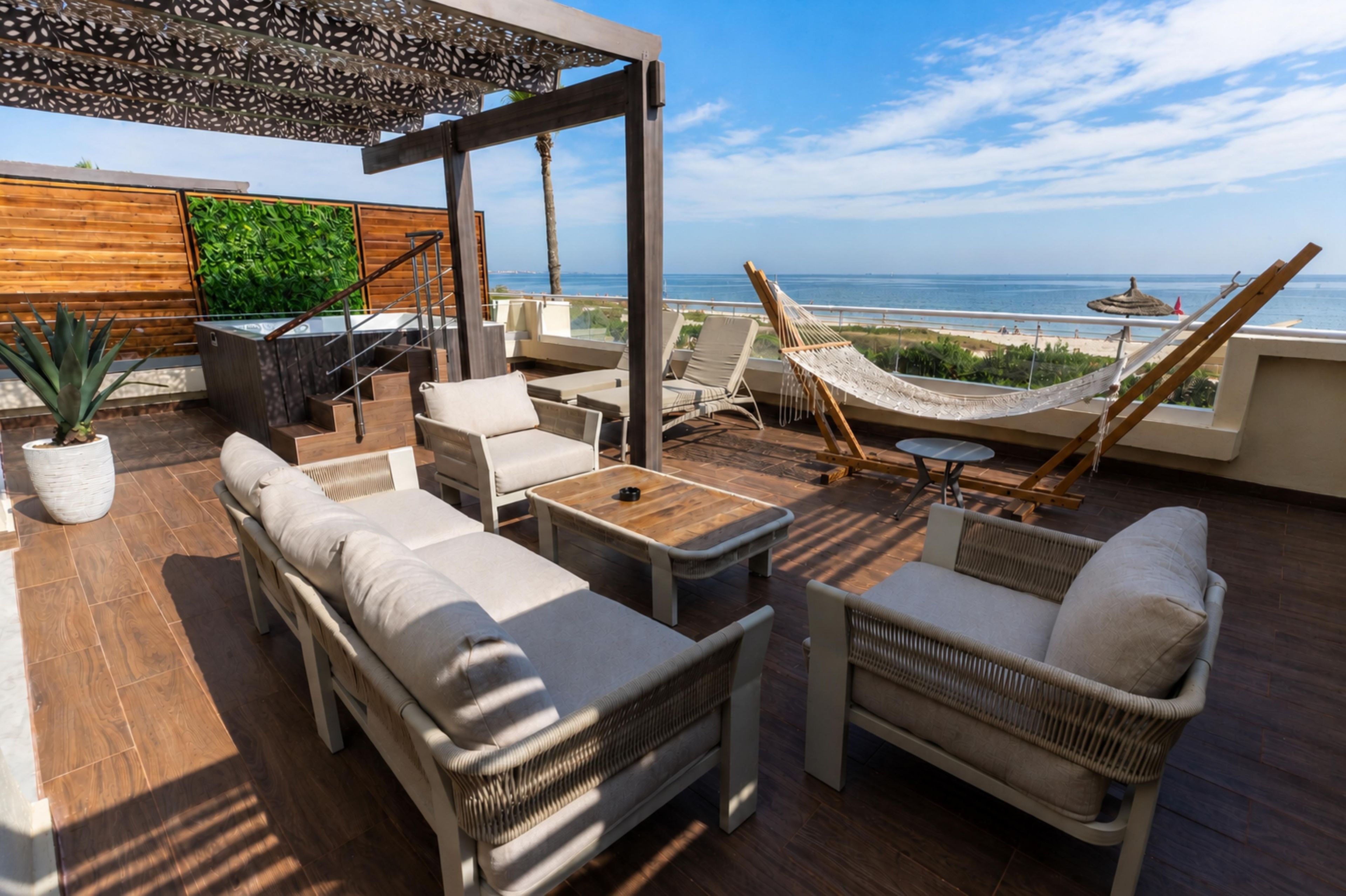 Une terrasse sur le toit avec des sièges extérieurs, un hamac et une vue sur la mer.