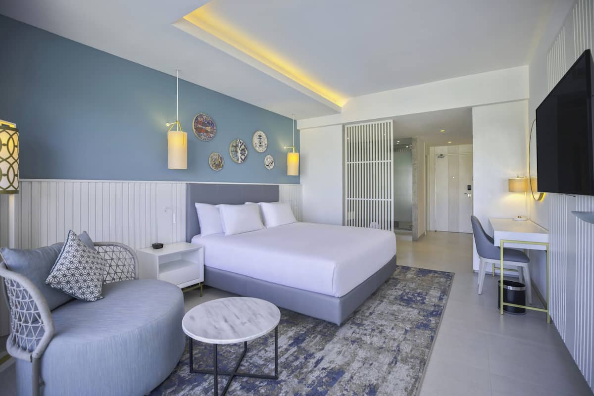 Un dormitorio moderno con una cama grande, mesitas de noche, un escritorio y una silla.