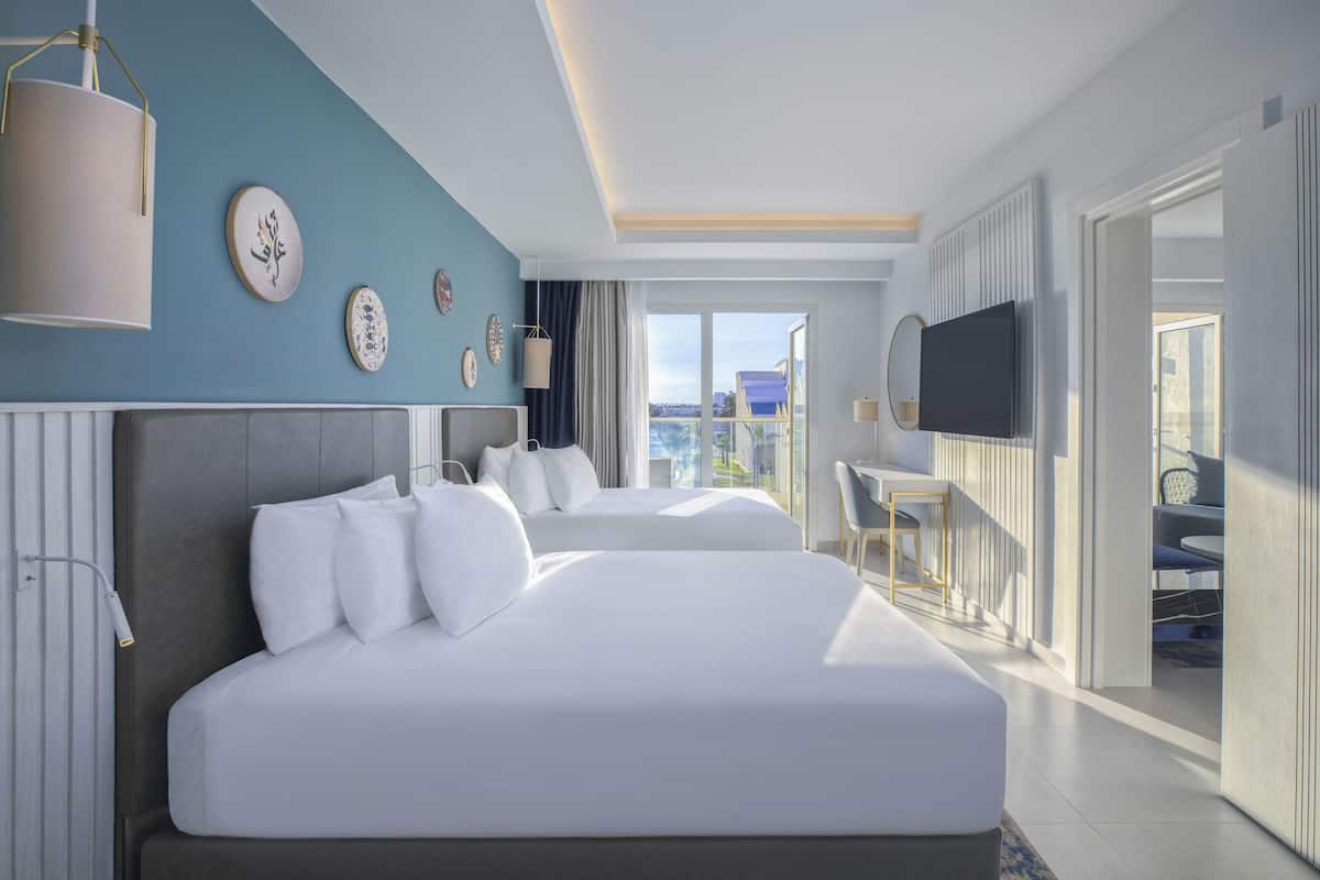 Una habitación de hotel moderna con una cama grande, un televisor y un balcón con vistas.
