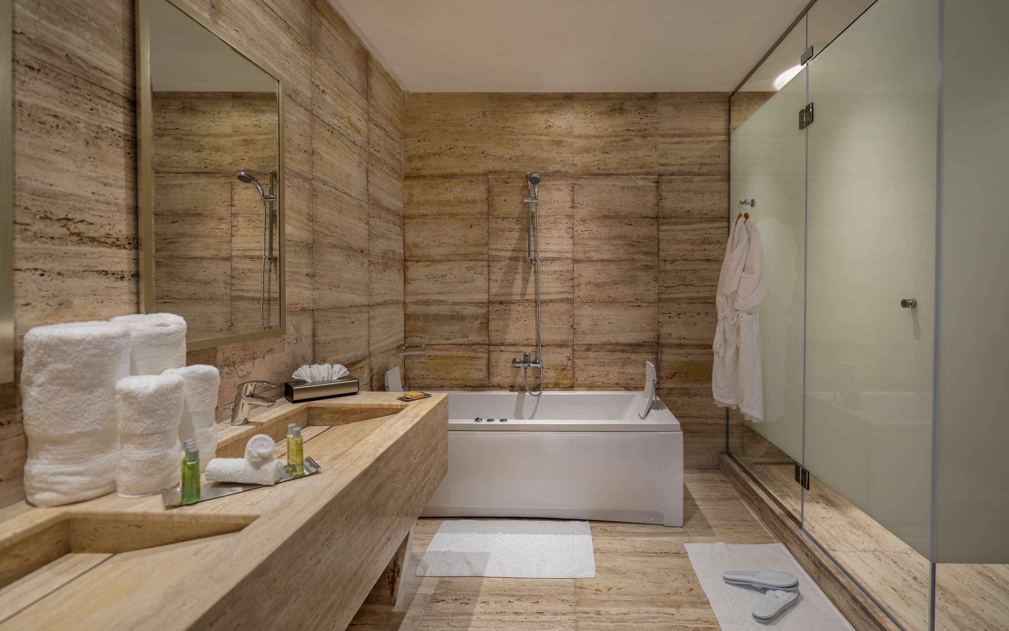 Un baño moderno con tocador de madera, bañera y cabina de ducha con mampara de vidrio.