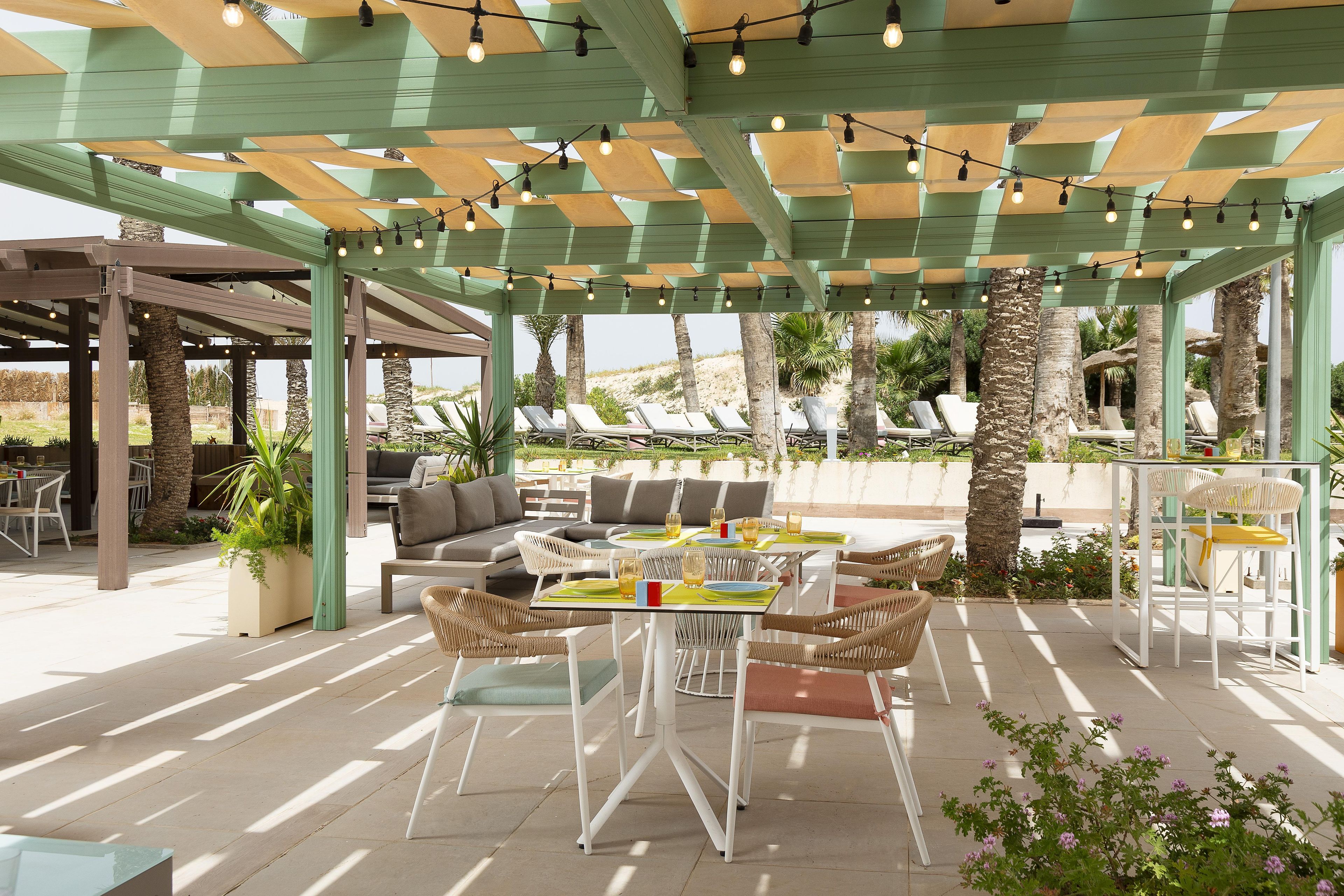 An outdoor patio with tables and chairs, a covered seating area, and a view of the landscape.