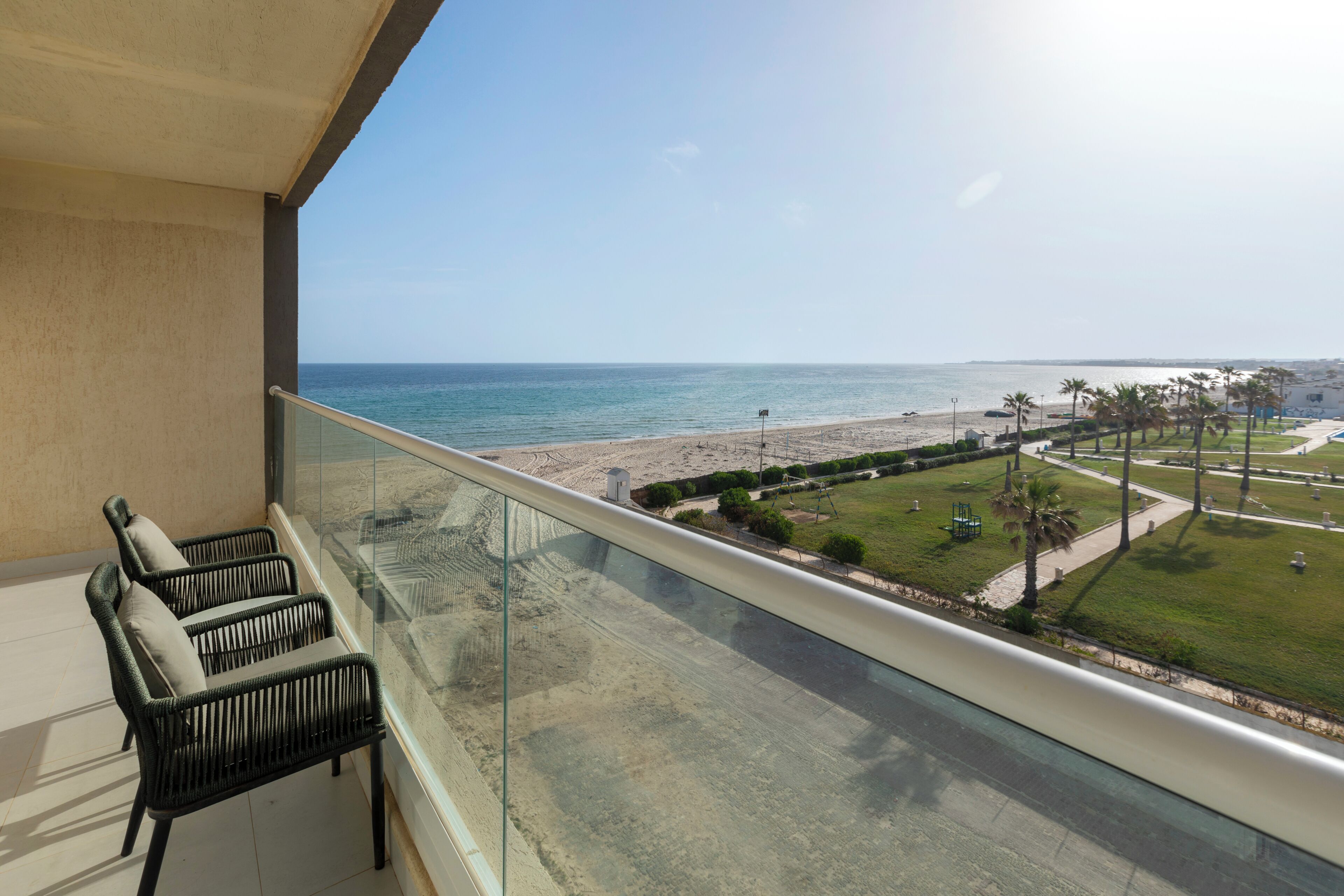 A balcony with a view of the beach and ocean.