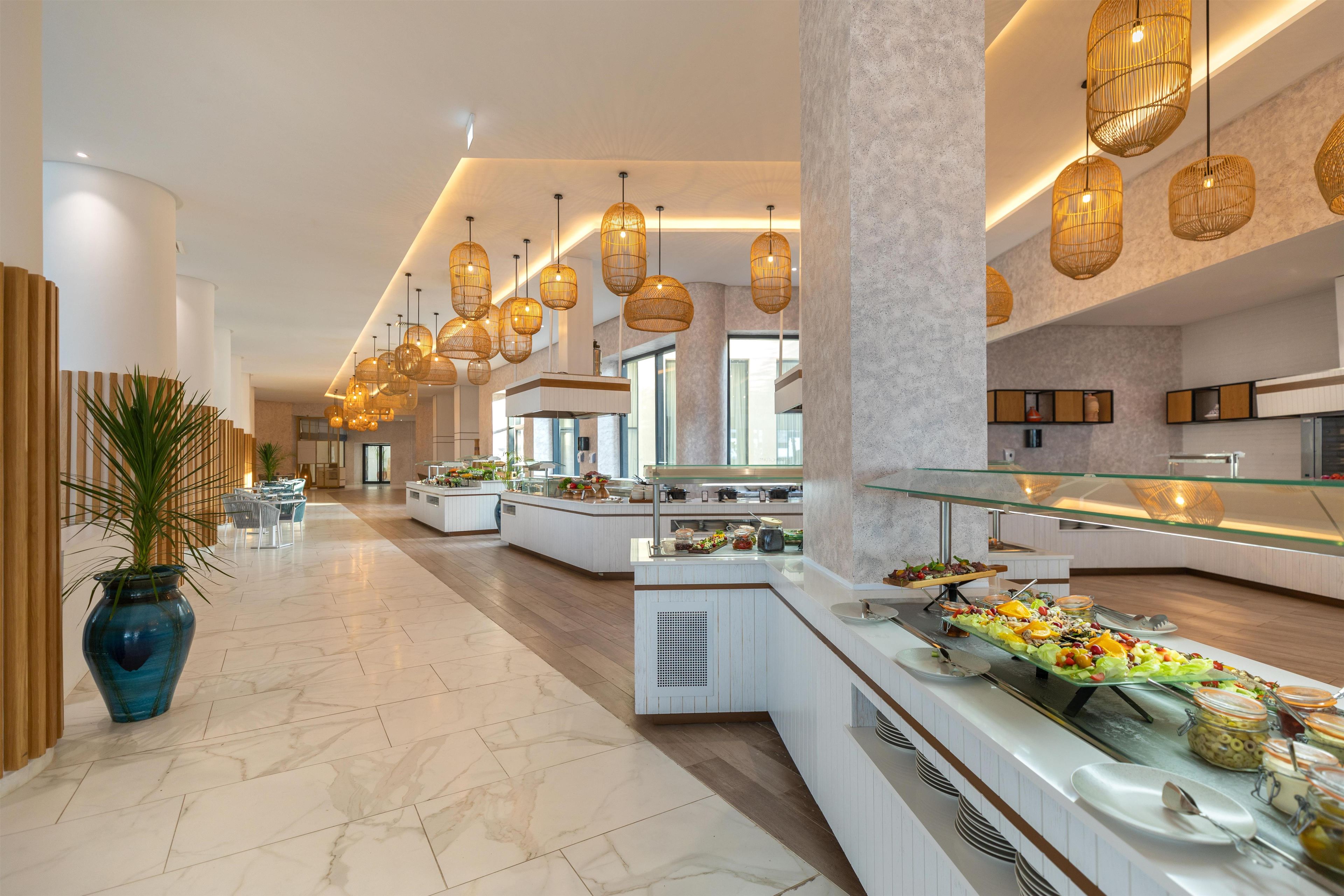 Eine geräumige Hotelhalle mit einem Buffetbereich, Marmorböden und hängenden Korbschwingenlampen.