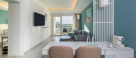 Una sala de estar moderna con un sofá, una mesa de centro y un televisor montado en la pared. Se ve un balcón a través de la puerta de cristal.
