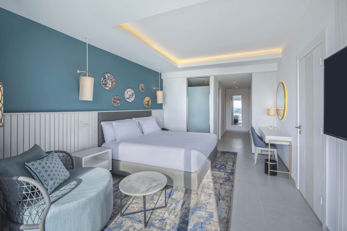 Una habitación de hotel moderna con una cama grande, un escritorio y una zona de estar.