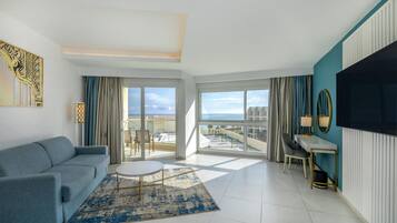 A modern living room with a sofa, a round coffee table, and a view of the sea through large windows.