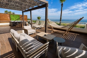 A sunlit outdoor lounge area with a hammock, lounge chairs, and a view of the sea. - Hilton Skanes Monastir Beach Resort (Monastir)