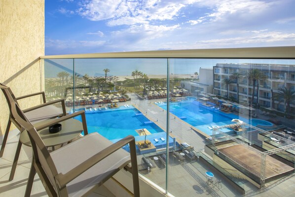 A rooftop pool area with multiple pools, lounge chairs, and umbrellas.