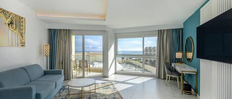 Una sala de estar moderna con un sofá, una mesa redonda de centro y vistas al mar a través de amplios ventanales.