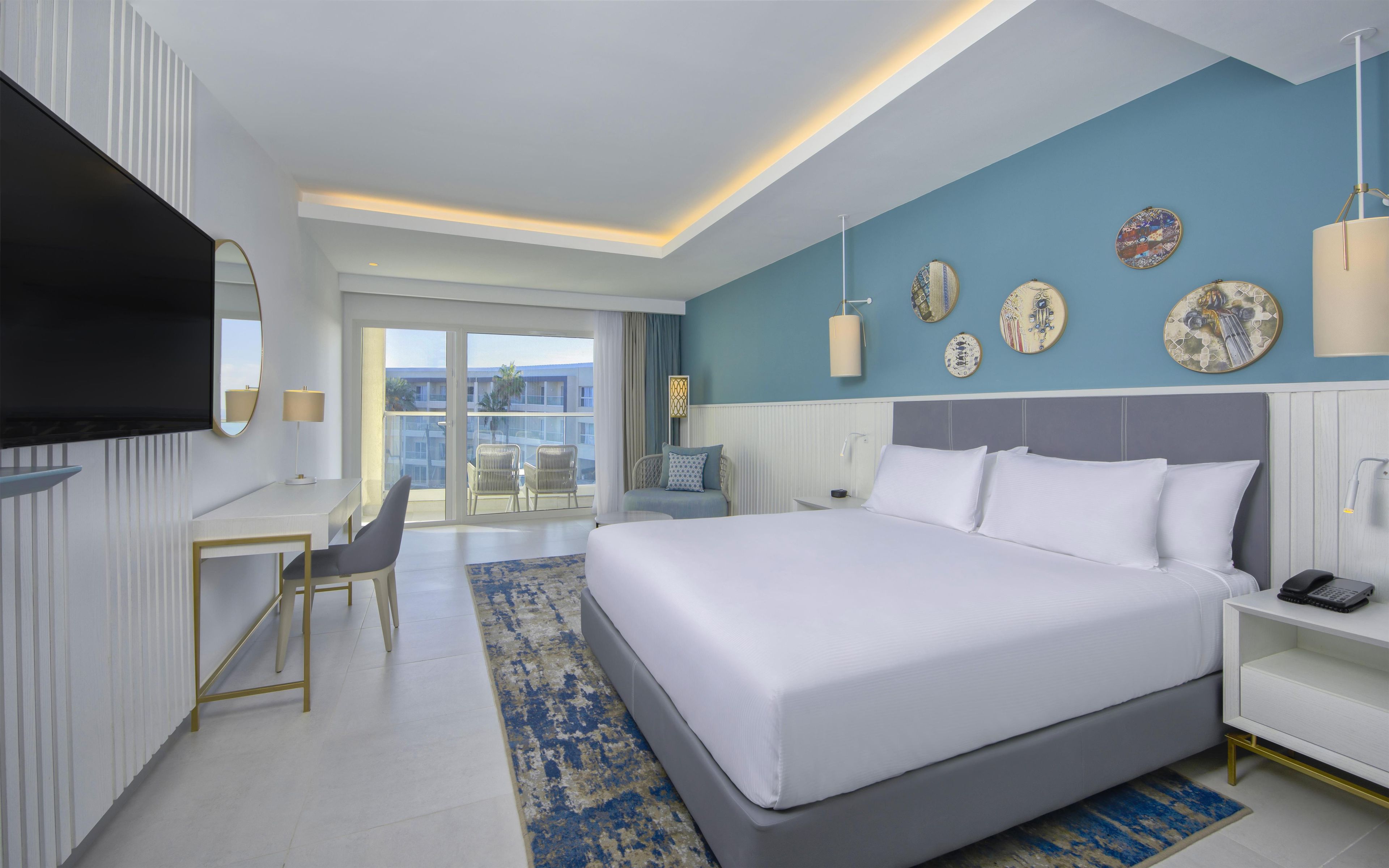 Habitación de hotel moderna con una cama grande, un escritorio y vistas a la ciudad.