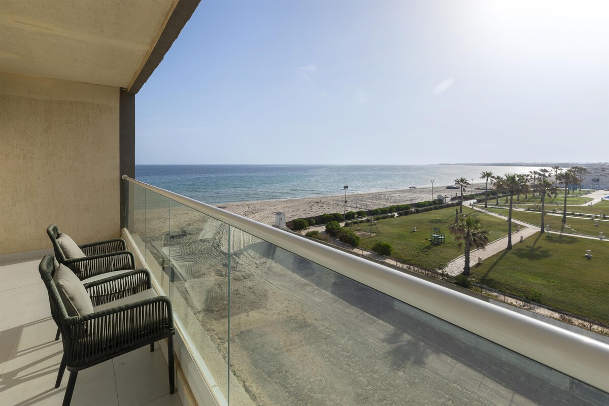 Un balcón con vista a la playa y palmeras.