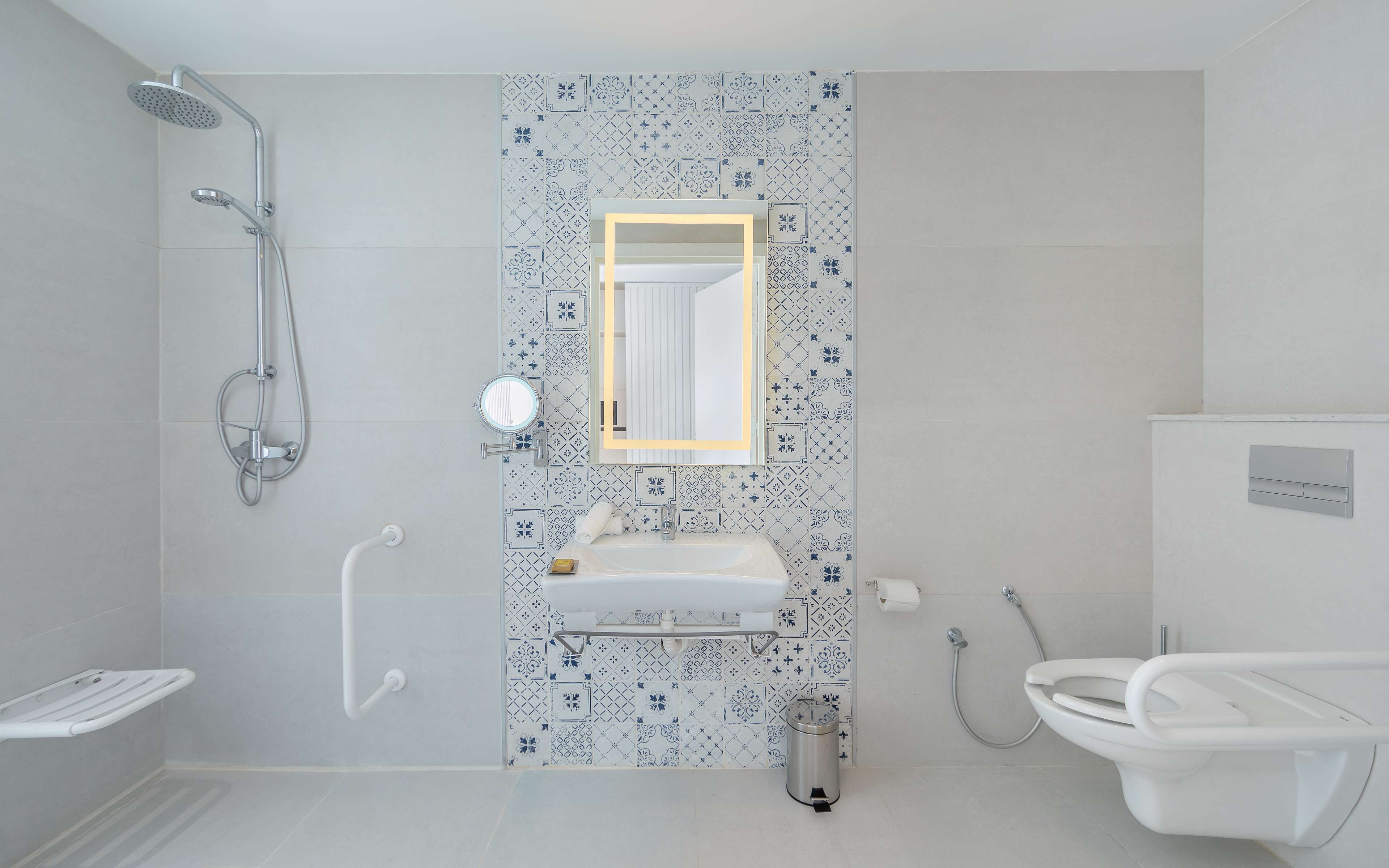 A bathroom with a shower, toilet, sink, and a mirror.
