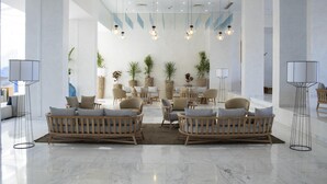 Un salon spacieux et moderne, doté de canapés en bois, de plantes en pot et de luminaires suspendus.
