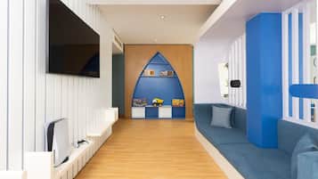 Ein zeitgemäßer Spielraum für Kinder mit einem blauen Spielhäuschen, einer Couch und einem Fernseher.