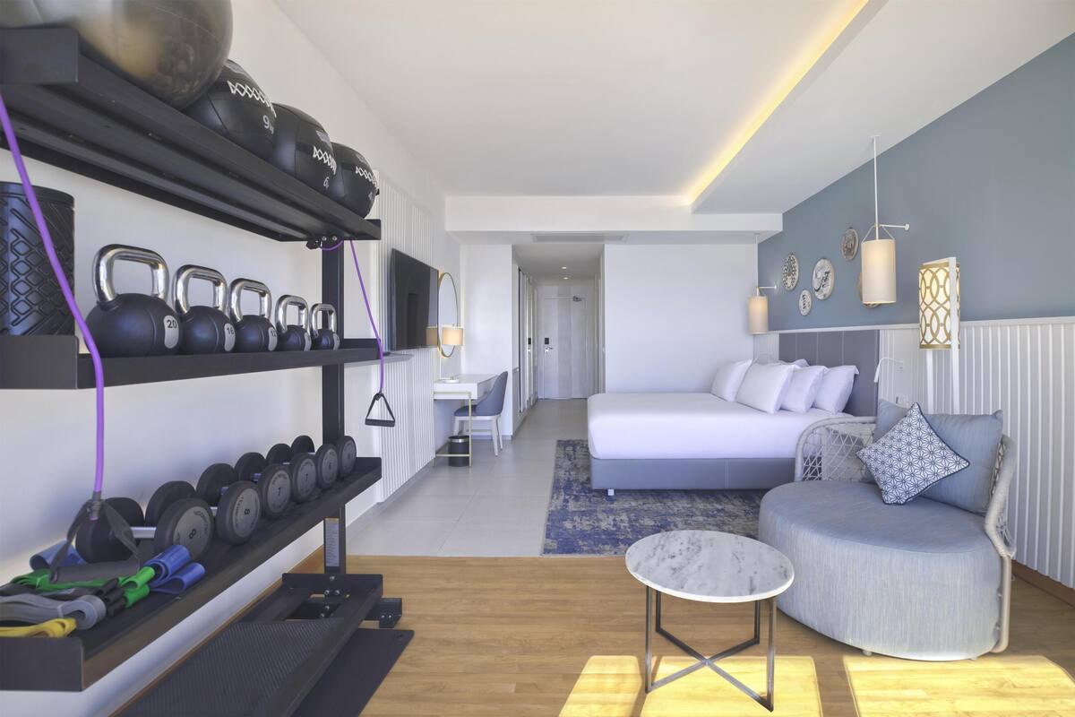 Ett modernt hotellrum med ett träningsområde, en säng och en sittgrupp.