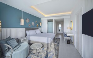 Une chambre d’hôtel moderne équipée d’un lit, d’un coin salon, d’un bureau et d’une télévision.