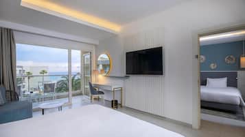 A hotel room with a large bed, a desk with a chair, a TV, and a balcony with a view.