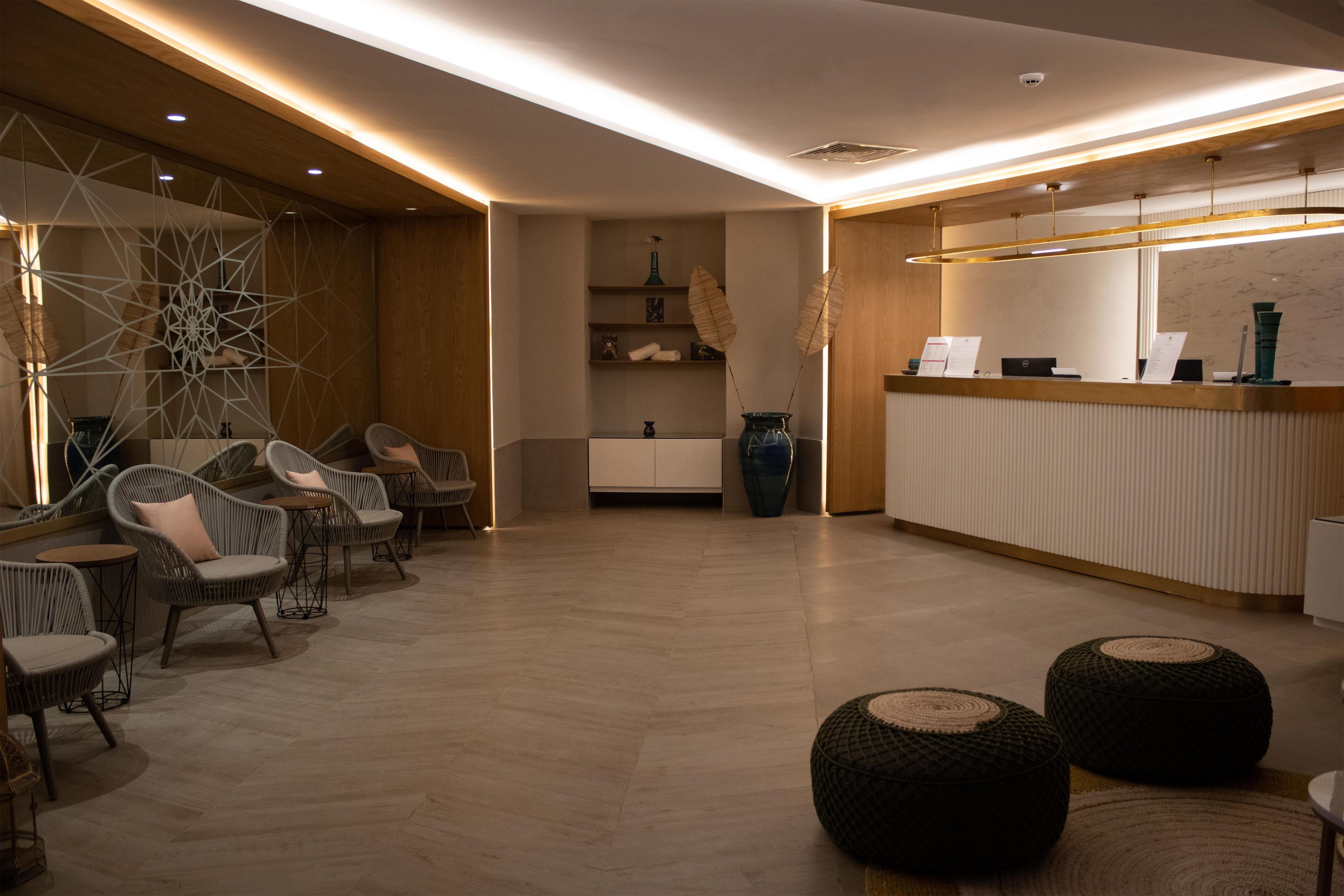 Een moderne hotellobby met zitplaatsen, een receptiebalie en decoratieve elementen.