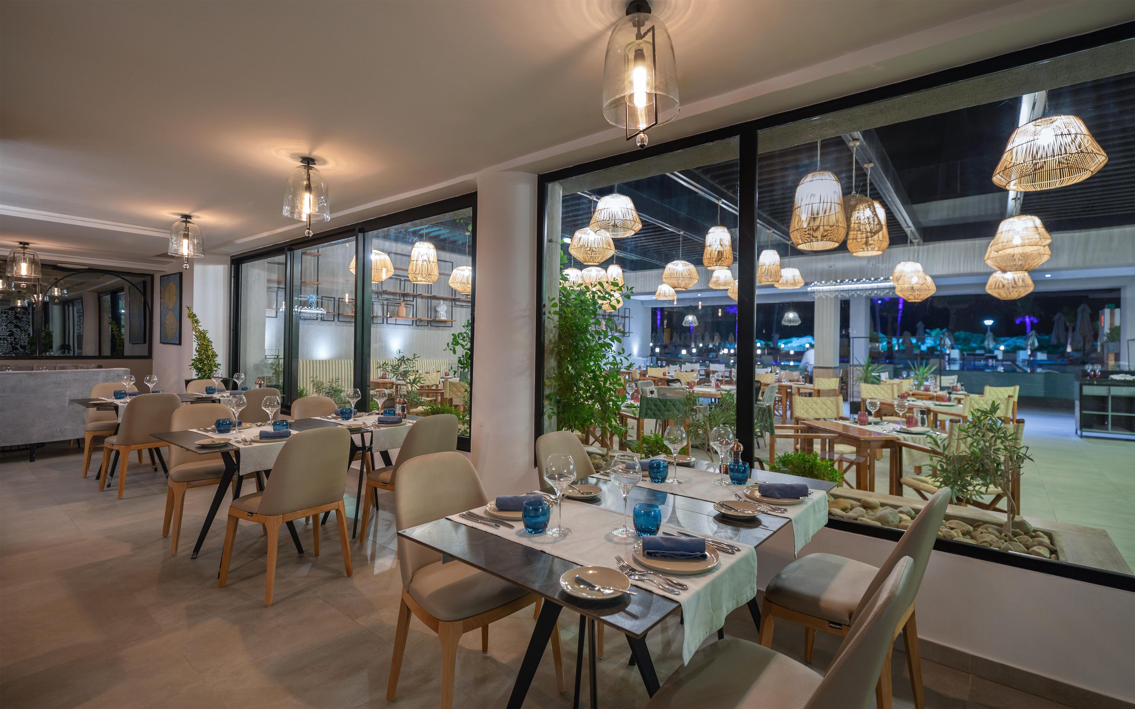Un restaurante con varias mesas, sillas y lámparas colgantes.