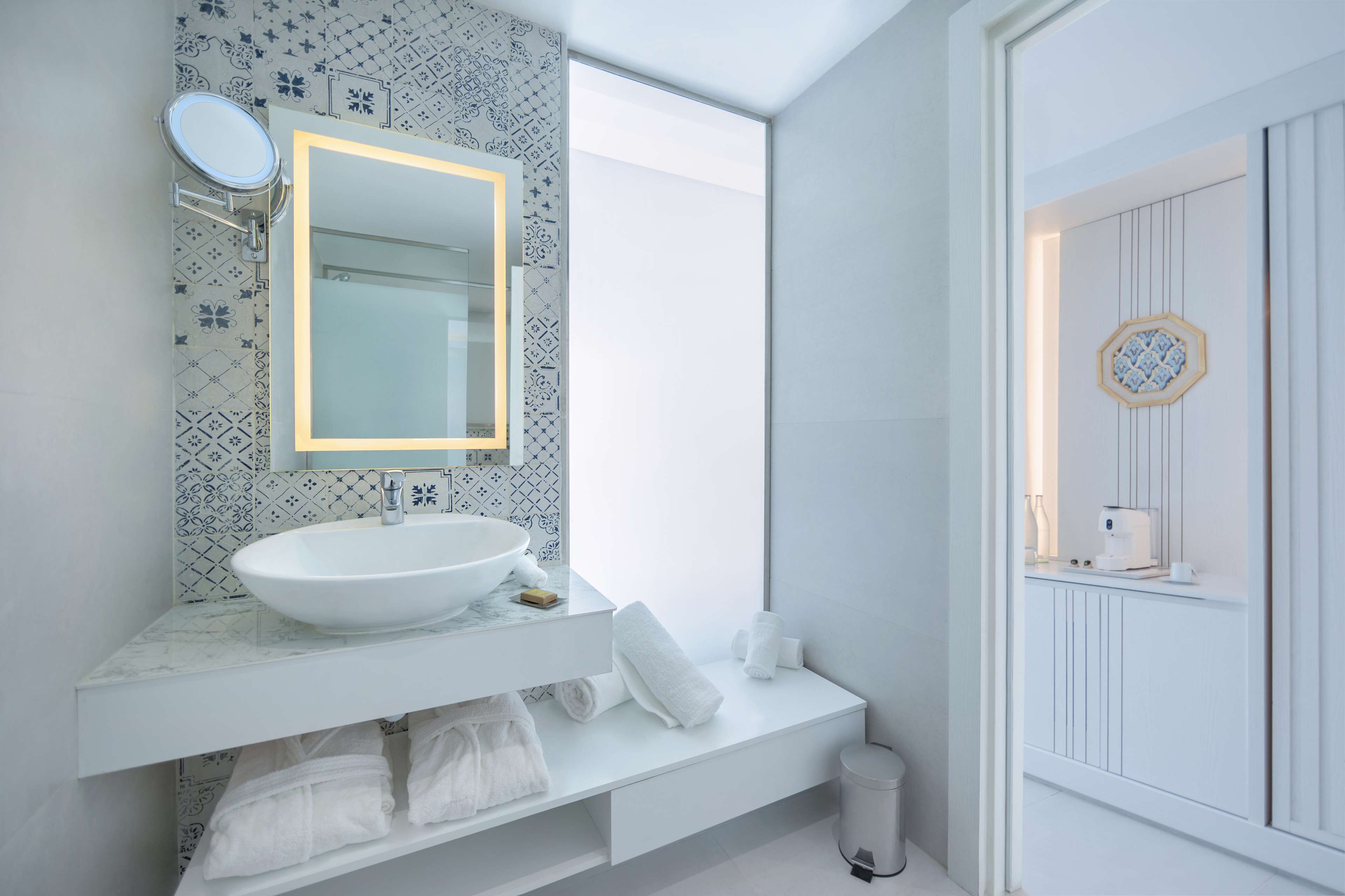 A modern bathroom with a white sink, mirror, and patterned tiles.
