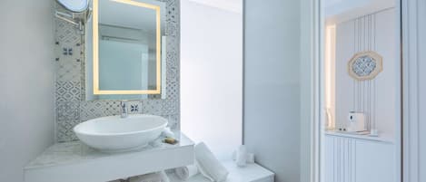 A modern bathroom with a white sink, mirror, and patterned tiles.