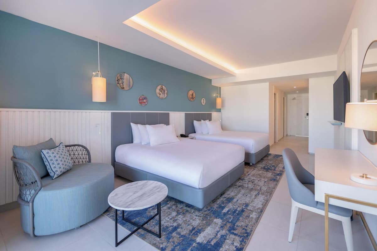 Una habitación de hotel moderna con dos camas, una zona de estar y un escritorio.