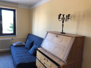 Un dormitorio con cama, tocador, ventana y un candelabro.