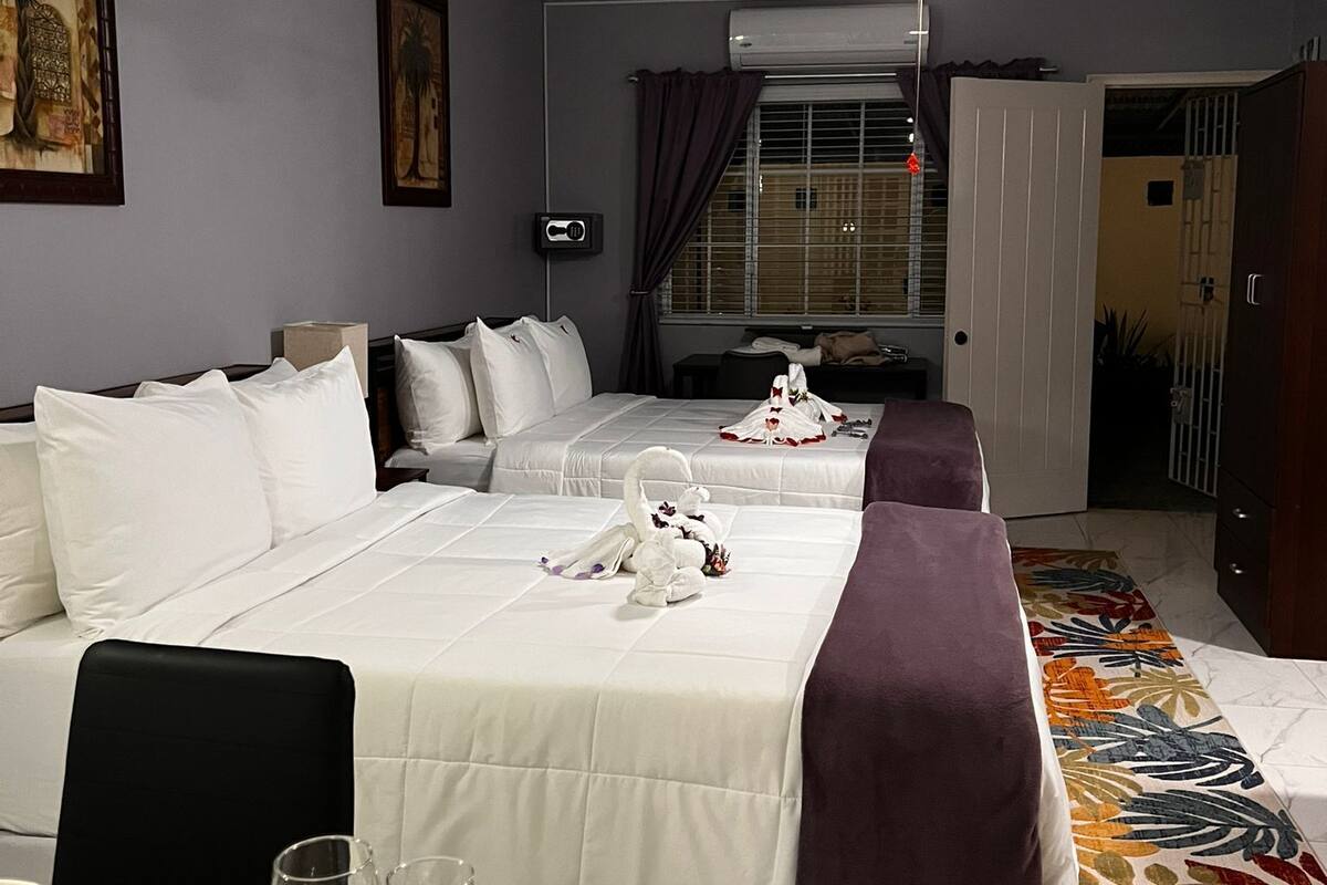 A hotel room with two beds, a dining table set with plates and glasses, a ceiling fan, and artwork on the walls.