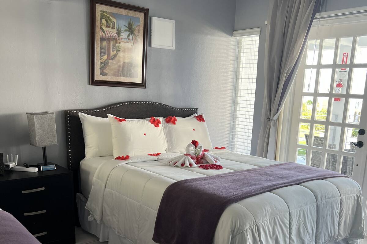 A neatly arranged bedroom with a bed, bedside table, and a window with curtains.