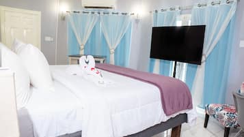 A hotel room with a bed, a TV mounted on the wall, a chair, and a desk.