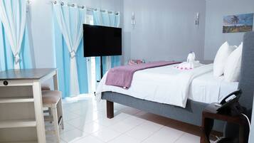 A hotel room with a bed, a desk, a television, and curtains.
