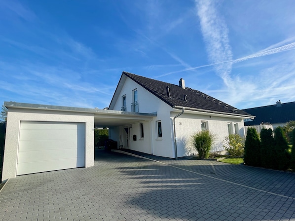 Une maison à deux étages avec un garage, une allée couverte et une pelouse bien entretenue.