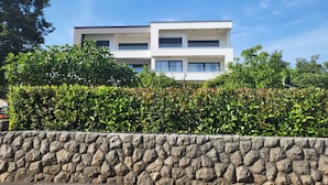 A modern two-story building with a stone wall in the foreground. - Holiday flat just 200m from the beach (Vantačići)