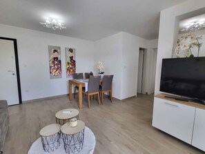 Un salon moderne comprenant un coin repas, un téléviseur à écran plat et des œuvres d’art accrochées aux murs.